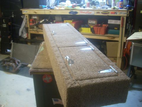 1992 Ford Bronco - A shop-built storage box wrapped in tan automotive carpet sits on a workbench cabinet, its long lid split into hinged sections with chrome…