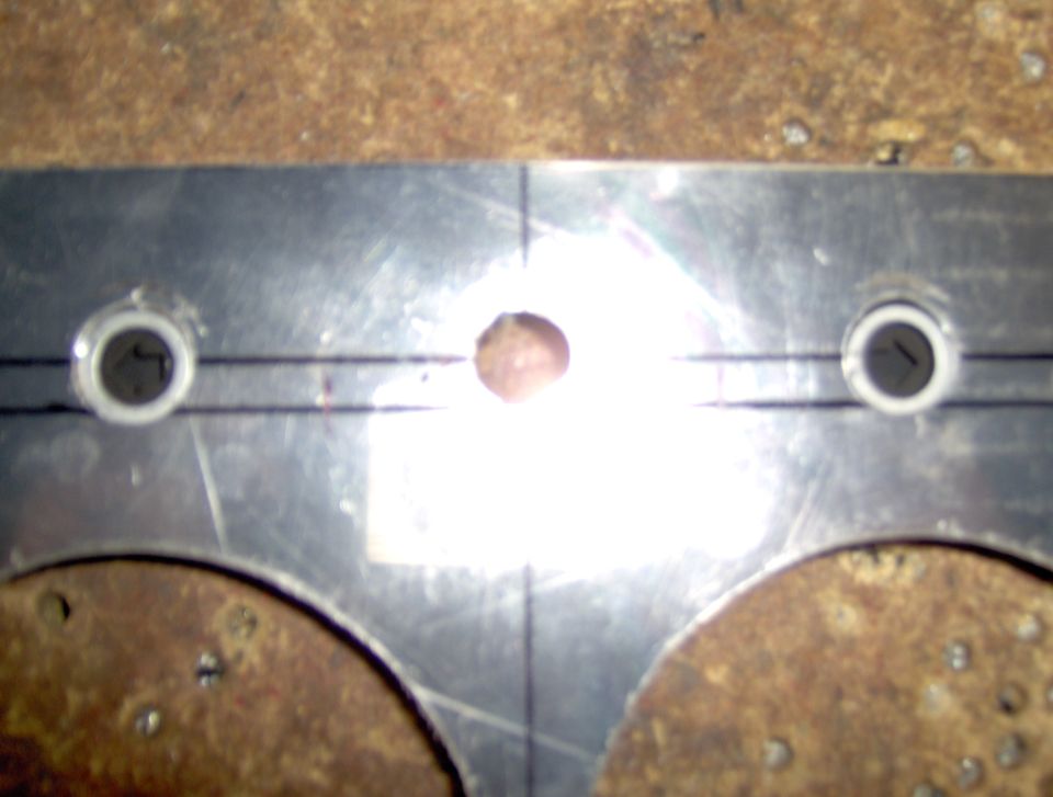 Metal plate with two grommeted holes and center hole, marked with lines