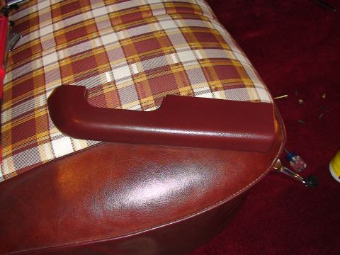 1979 Ford F-150 - Close-up of a maroon door pull handle resting on plaid seat upholstery, with visible screws and tools nearby.