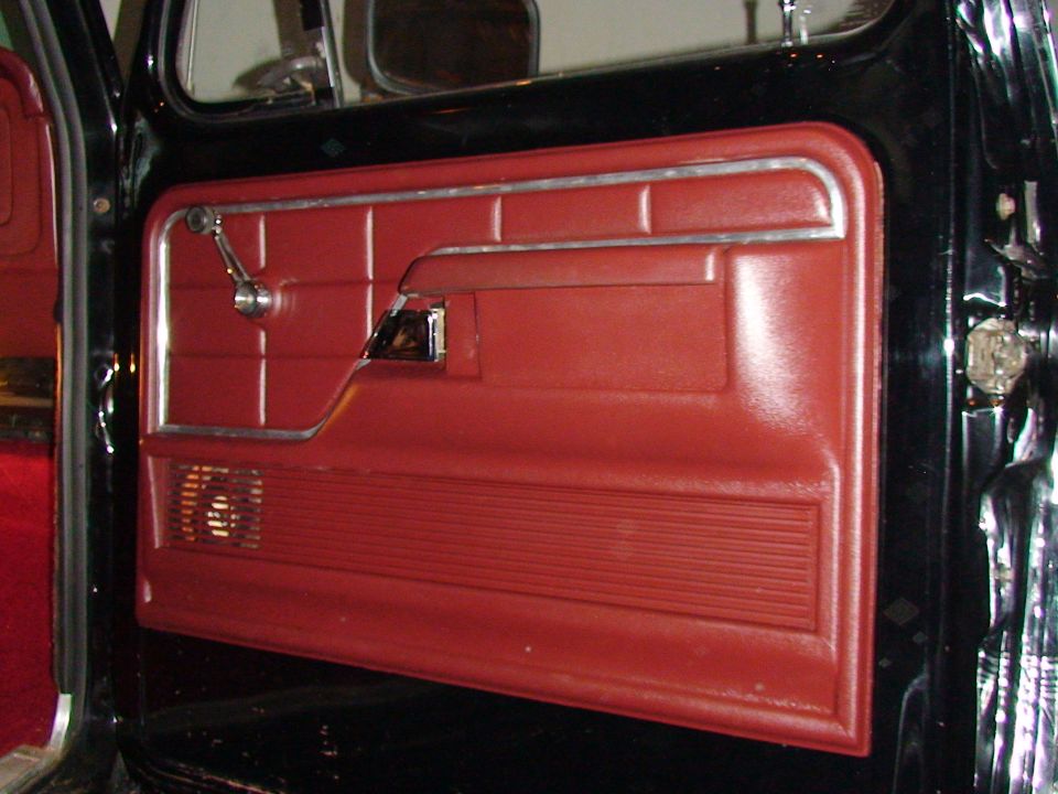 Close-up of a red truck door panel with chrome window crank and door handle
