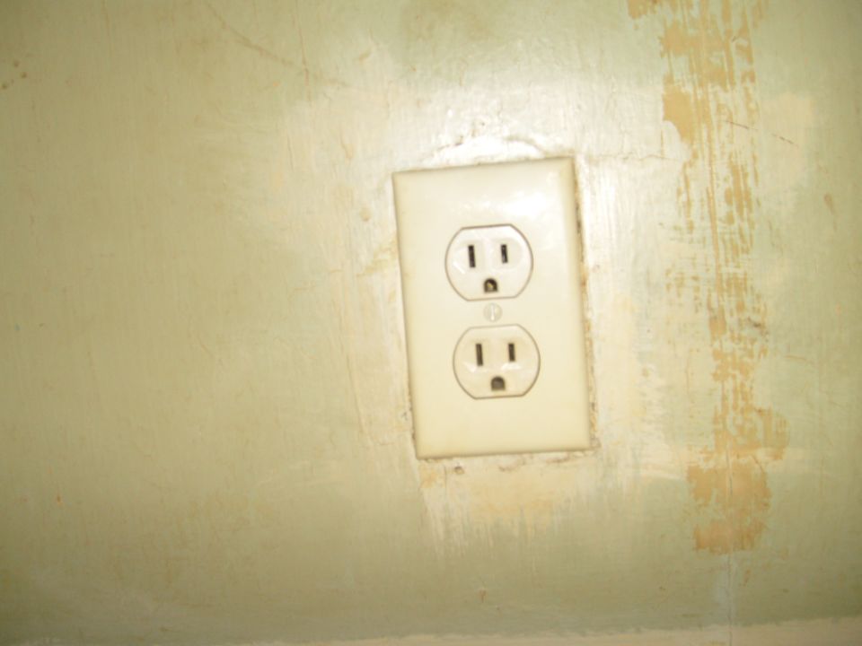Cream electrical outlet on a patchy pale green wall