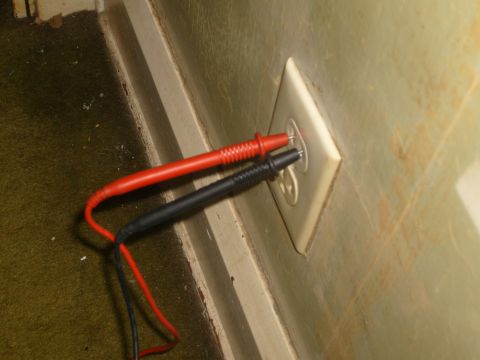 1993 Ford Bronco - Multimeter probes are inserted into a wall outlet.