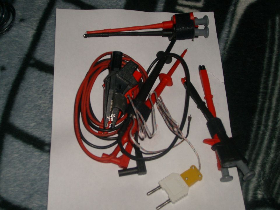 Bundle of red and black test leads with alligator clips and probe ends, plus a yellow and white adapter plug
