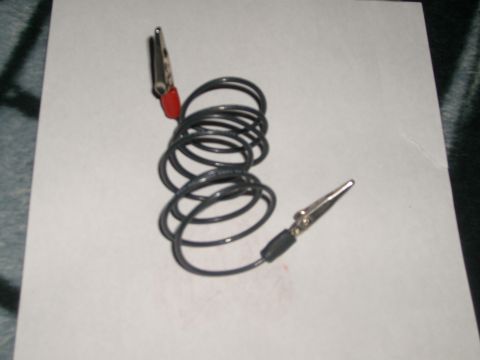 1993 Ford Bronco - A coiled test lead / jumper wire with a red-handled alligator clip on one end and a metal probe or connector on the other, laid on a sheet…