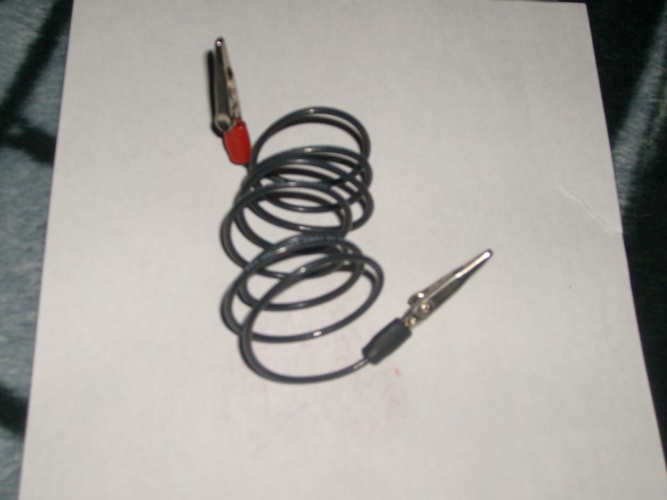 Coiled test lead with red alligator clip and metal probe on white paper