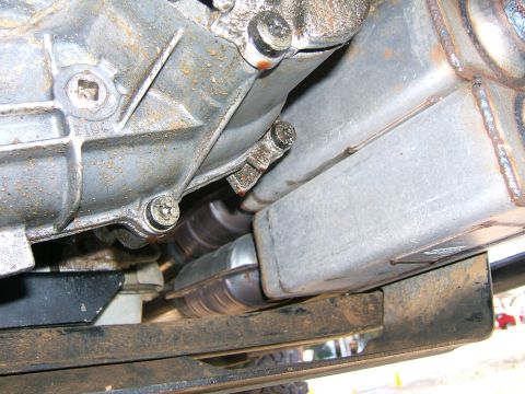 1991 Ford Bronco - Close-up view of the exhaust system and transmission components from underneath a vehicle.