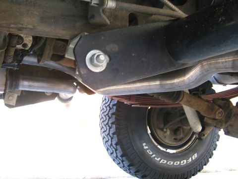 1991 Ford Bronco - Close-up of the rear suspension and exhaust system of a vehicle, showing leaf springs and a tire.