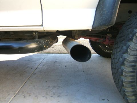1991 Ford Bronco - A close-up view of a vehicle's undercarriage, focusing on the exhaust system and a tire.