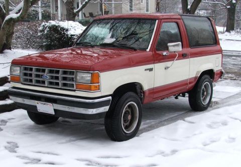 1989 Ford Bronco II - A two-tone red and white Ford Bronco II sits in a snowy environment.