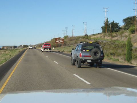 1996 Ford Bronco - Driving on the highway behind a 1996 Ford Bronco, with a red truck on a trailer in the distance.