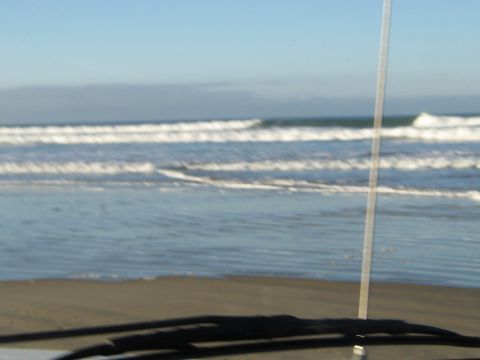 1996 Ford Bronco - A view of the ocean from inside a vehicle, with waves rolling onto the shore.