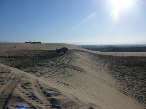 1988 Ford Bronco - Vehicle navigates sandy terrain with tire tracks visible on the dunes.