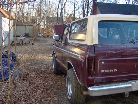 1996 Ford Bronco - Rear view of a maroon Ford Bronco with a white removable top. The hood is open.