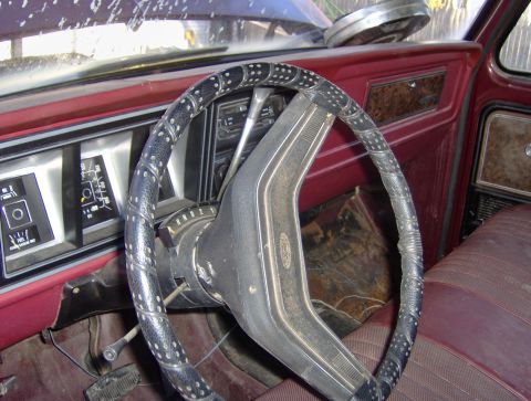 1996 Ford Bronco - The interior of an older vehicle shows a worn steering wheel and dashboard with visible gauges.