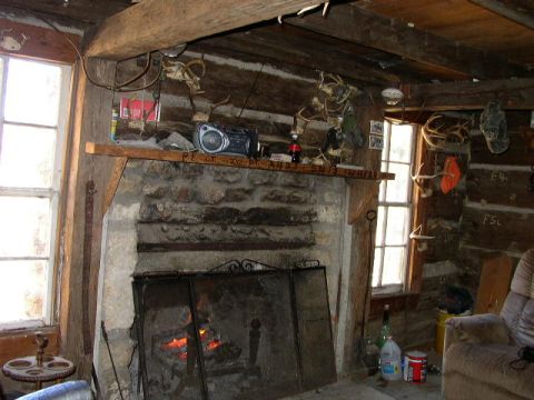 1995 Ford Bronco - A cozy cabin interior features a roaring fire in the stone hearth, with hunting trophies adorning the log walls.