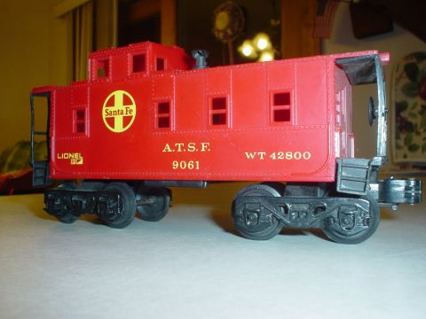 2000 Ford Crown Victoria - A red Lionel Santa Fe caboose toy is shown from the side with visible text and markings.