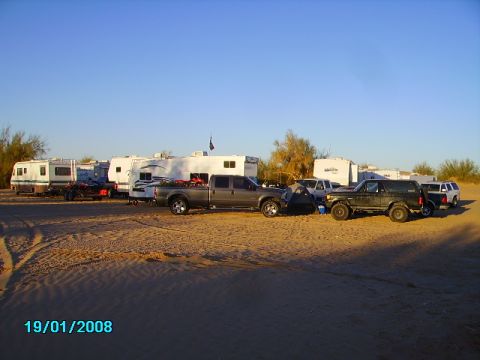 1990 Ford Bronco - A desert campsite scene with multiple vehicles and RVs under a clear blue sky.