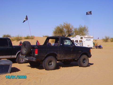 1990 Ford Bronco - A black 1990 Ford Bronco is seen in a desert landscape with other vehicles and RVs.
