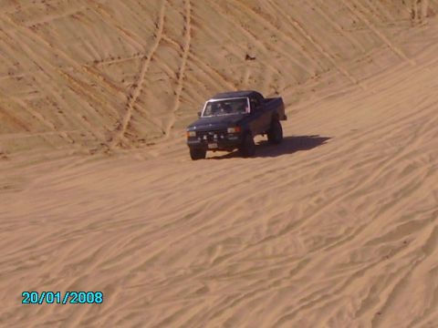 1990 Ford Bronco - A dark blue 1990 Ford Bronco navigates sandy terrain, captured in a desert scene.