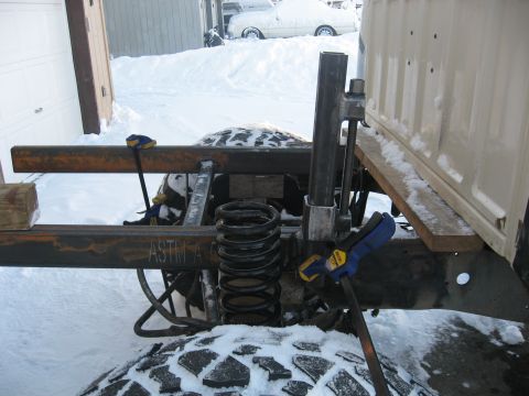 1990 Ford F-250 - Close-up of truck frame and suspension components during winter work.