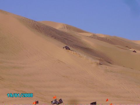 1990 Ford Bronco - Vehicles navigate a sandy desert landscape under a clear blue sky.