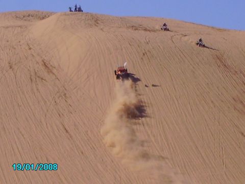 1990 Ford Bronco - Multiple off-road vehicles navigate a sandy desert landscape on a clear day.