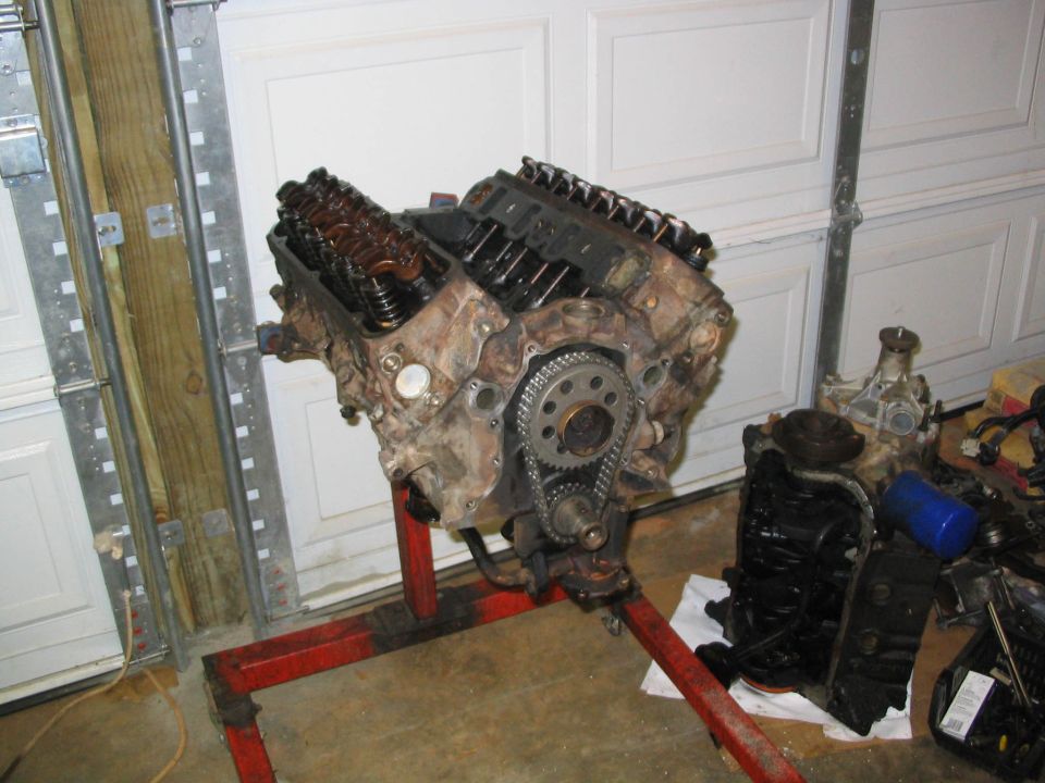 V8 engine on red stand with exposed timing chain in a garage