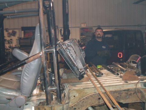 1995 Ford Bronco - A man stands in a workshop, surrounded by parts of a vehicle undergoing modification.