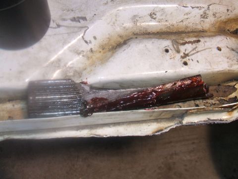 1995 Ford Bronco - Detail of corroded metal and lubricant, likely from a vehicle's undercarriage or frame.
