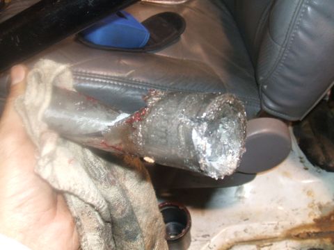 1995 Ford Bronco - A damaged metal pipe, possibly from a vehicle repair, is held with a rag. Blood and metal shavings are visible.
