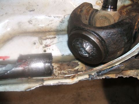 1995 Ford Bronco - Close-up view of a damaged driveshaft universal joint and corroded vehicle frame.