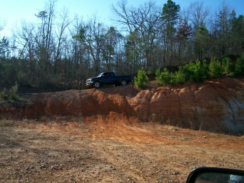 1993 Ford Bronco - A dark pickup truck navigates a dirt embankment under a clear sky.