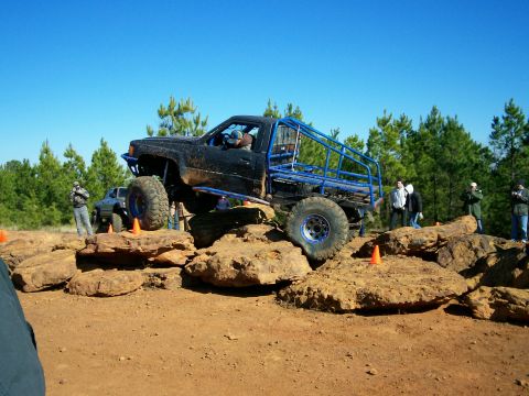 1993 Ford Bronco - Custom off-road truck navigates a rocky obstacle course with spectators watching.