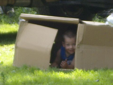 1989 Ford Bronco - A young child peeks out from a cardboard box while sitting in the grass.