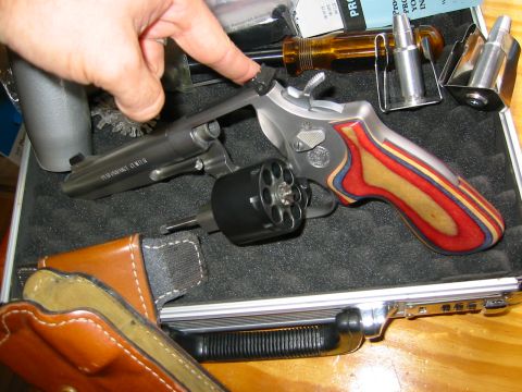 1996 Ford Bronco - A revolver with distinctive laminated grips is shown with its cylinder open, alongside ammunition and a holster.