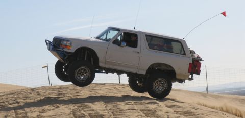 1984 Ford Bronco - This modified Ford Bronco is captured mid-air while traversing a sand dune.