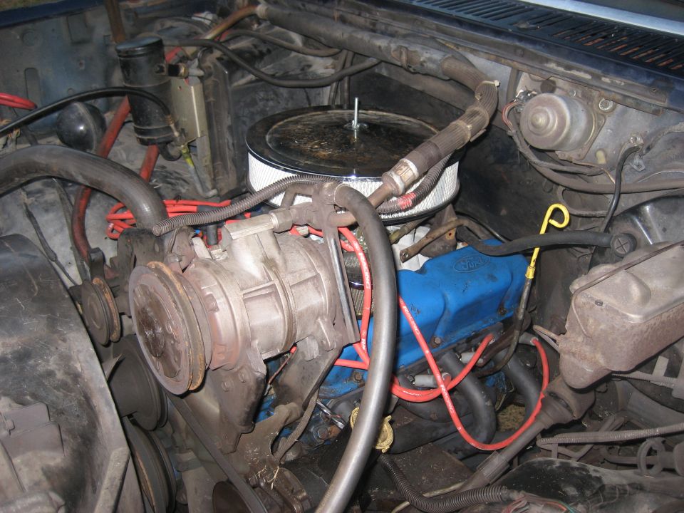 Engine bay with blue Ford valve covers, air filter, and AC compressor