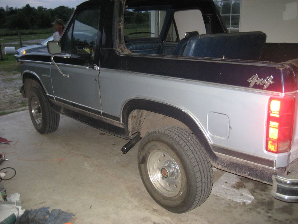 Silver and black Ford Bronco with a 4x4 badge, seen from the rear three-quarter angle