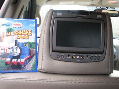 1991 Ford Bronco - A DVD player is mounted on a car's headrest, next to a children's movie case.