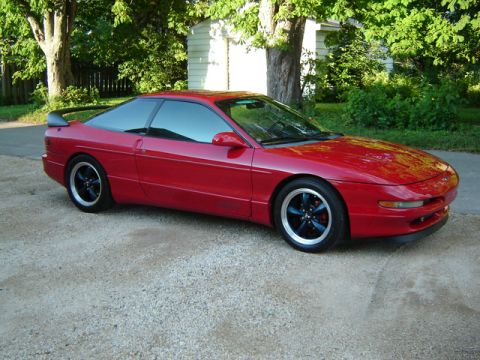 1993 Ford Probe - A red 1993 Ford Probe is shown from a three-quarter front angle, parked outdoors on a gravel surface.