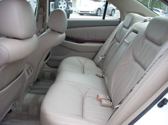 Tan leather rear bench seat interior of a sedan with wood-grain door trim