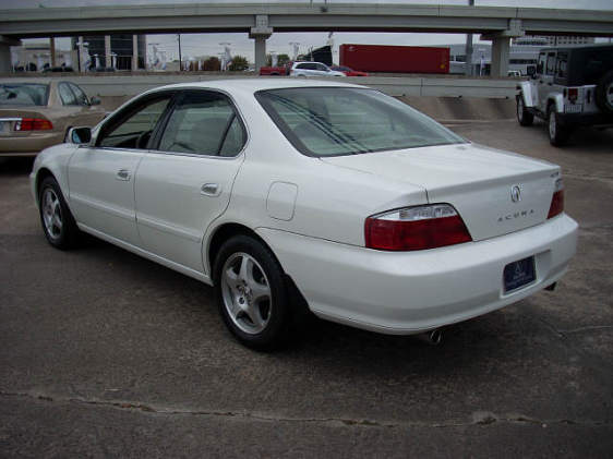 White Acura TL sedan rear three-quarter view on a concrete lot with alloy wheels