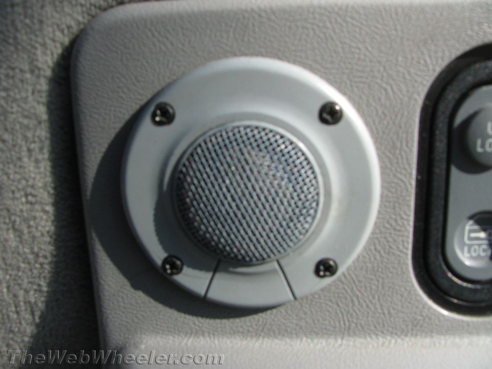 Close-up of a car's interior door panel showing a speaker and power window controls