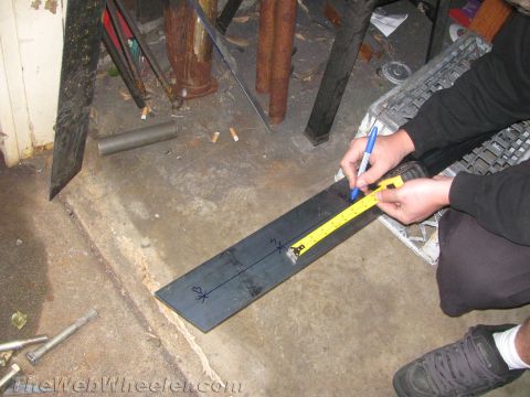 1987 Suzuki Samurai - A person measures and marks a metal bar, possibly for a vehicle modification.