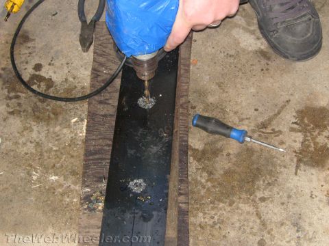 1987 Suzuki Samurai - A drill press is used to create holes in a black metal plate, likely for custom vehicle parts.