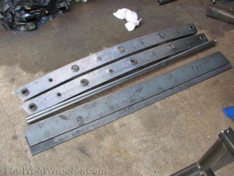 1987 Suzuki Samurai - Metal components, possibly for vehicle rock sliders, are laid out on a workshop floor.