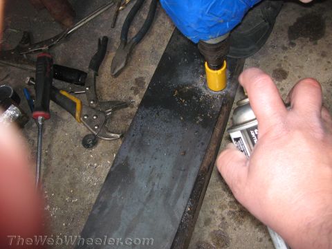 1987 Suzuki Samurai - A person drills a hole in a metal plate, with various tools scattered around.