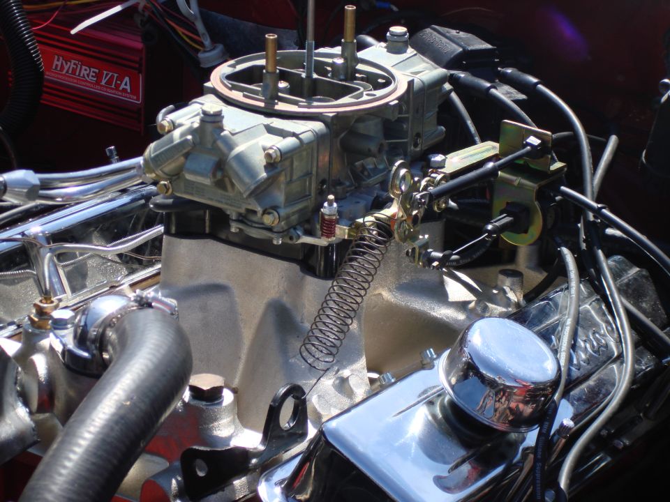 Close-up of a carburetor on an engine, with a red Hyfire VI-A ignition box visible