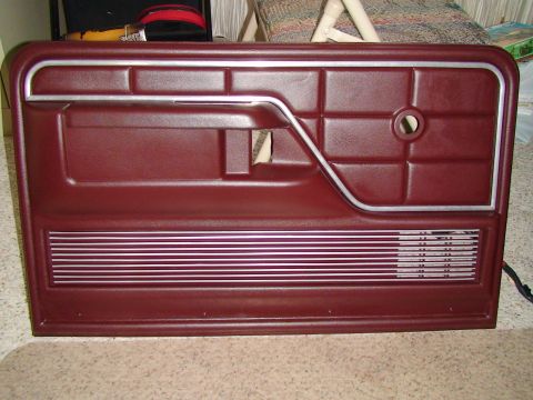 1979 Ford F-150 - Maroon car door panel with silver trim and horizontal speaker grille is shown.