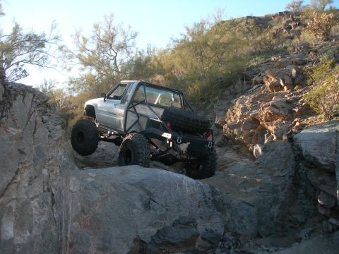 1986 Toyota Hilux - A modified Toyota pickup truck tackles a challenging rocky terrain.